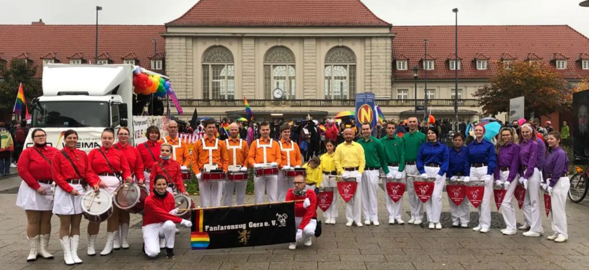 Der Fanfarenzug Gera in bunten Formationshemden bei einem Umzug, mit Vereinsbanner